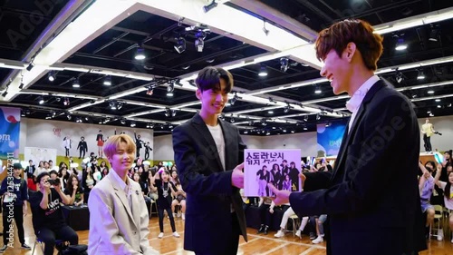 Enthusiastic Fans at a K-Pop Group's Fan Meeting, Raising Lightsticks