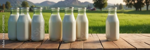 Milk bottles arranged neatly on a wooden table in front of a picturesque meadow scene with grazing cows and lush green grass, cows, country, wood