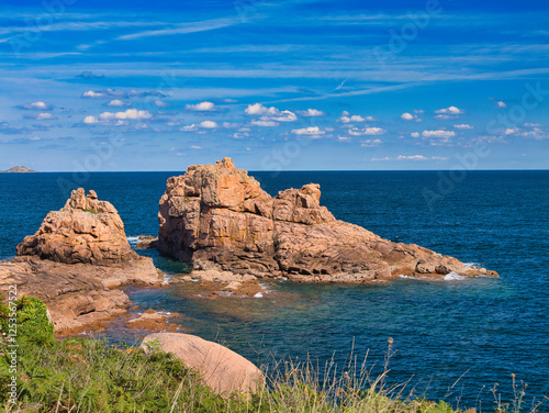 Rock formations on the famous Pink Granite Coast near Ploumanac'h in Perros-Guirec, Lannion, Brittany in Northern France. Taken on a sunny day in summer, with a blue sky and light cloud.