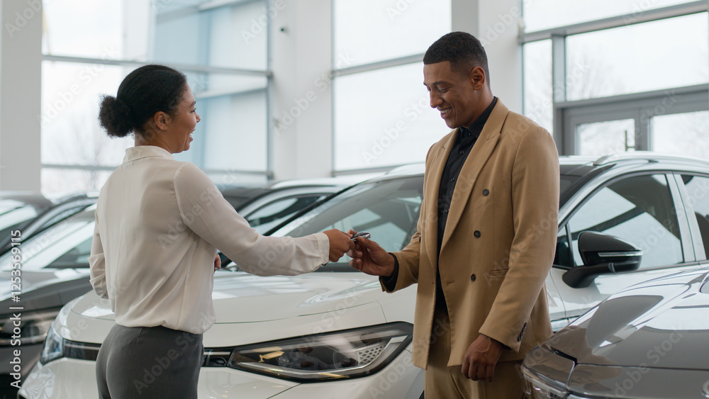 Fototapeta premium Auto dealer seller manager woman giving car key to happy owner African American man in dealership center successful sale customer rent buy new luxury automobile check modern electric auto alarm system
