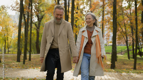 Happy Caucasian family retired married couple 60s old mature woman man going walking in city park autumn nature carefree wife husband love romantic relationship intelligent female male stroll together