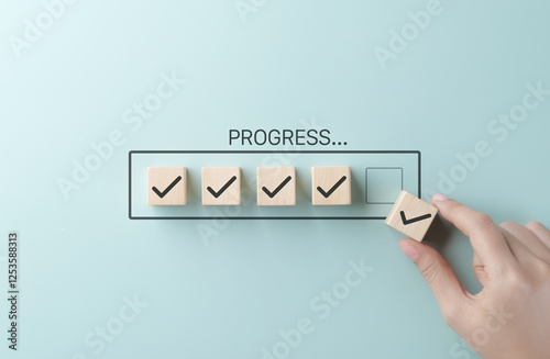 Checklist and task progress tracking concept. A hand placing the final checkmark on wooden blocks in a progress bar, task completion, productivity, goal setting, and efficient project management. photo