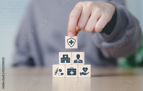 Health insurance and medical care concept. Woman placing wooden blocks with health-related icons, medical care, health insurance, and medication. healthcare services, protection, insurance coverage,
