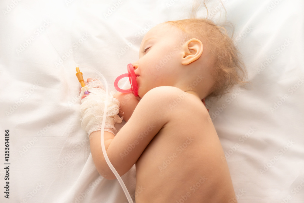 Babygirl sick and sleeping on patient bed at the hospital. Saline intravenous or (IV)drip in baby patient hand. Poor baby looks tired and exhausted.IV fluid replacement or correcting the dehydration