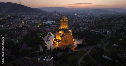 Drone shot of Sameba Cathedral, one of the most important symbols of Georgia. As the camera rotates, you can see this magnificent structure and the surrounding city of Tbilisi.