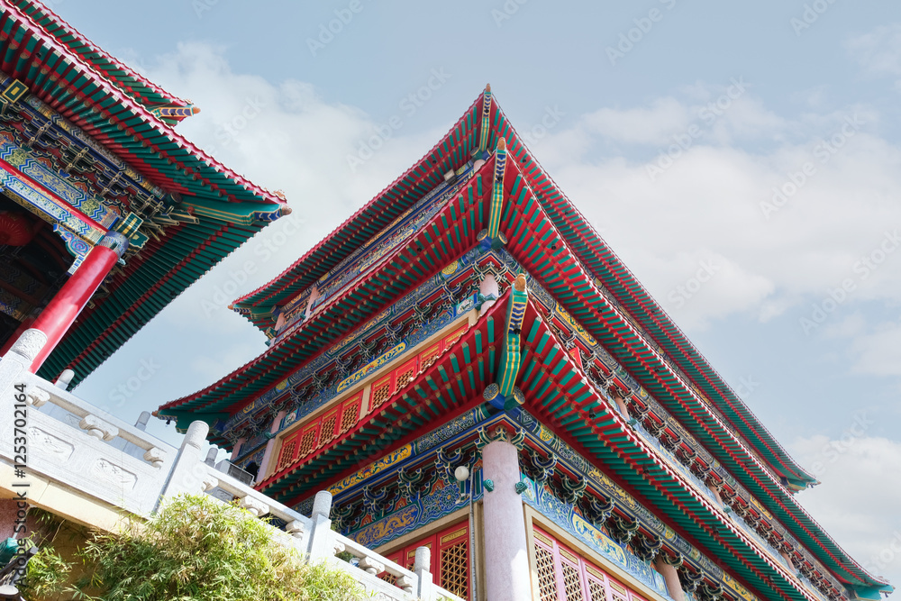 A majestic Chinese temple with intricate architecture, vibrant red and green roofs, and ornate details, standing gracefully against a bright blue sky, reflecting cultural heritage and tradition.