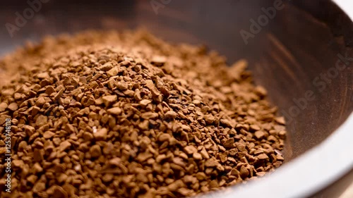 Granules of instant roasted caffeine-free coffee in wooden bowl. Unprocessed raw decaf drink ingredient. Front view. Rotation