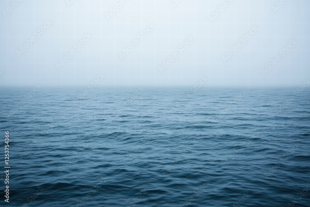 Obraz premium Serene Blue Ocean Water Under Soft Foggy Sky at Dawn