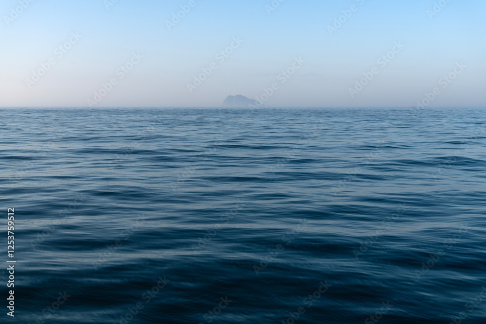 island in the fog on the sea at dawn
