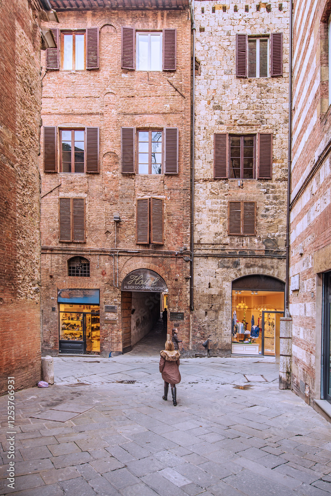 Obraz premium Facade of old buildings in the historical center of Siena, the UNESCO World Heritage Centre, unchanged for 13-14 centuries, with its medieval streets looked like in the early Middle Ages. Italy, 2019