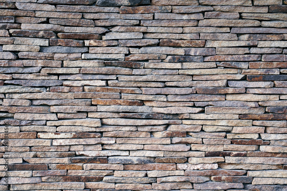 Fototapeta premium Wall of cut natural stone. Flat cut natural stone art arranged neatly or randomly on building walls and facades.