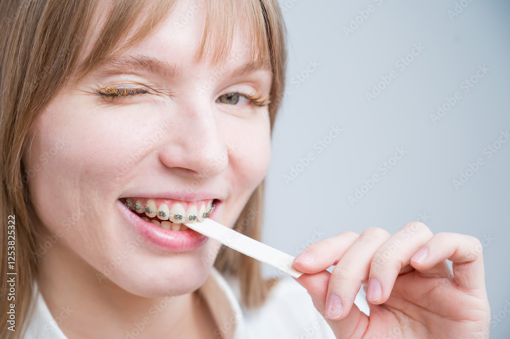 Young woman with metal braces on her teeth is chewing gum. The girl is eating gummy candy Young woman with metal braces on her teeth is chewing gum. The girl is eating gummy candy