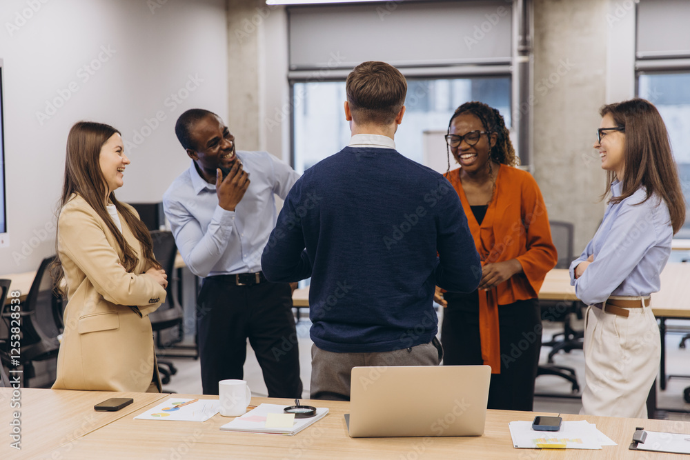 Obraz premium Diverse colleagues enjoying a lighthearted moment during a productive workday, fostering a positive and inclusive work environment