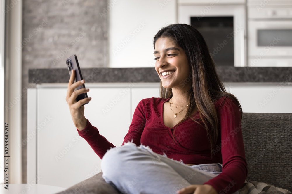 Pretty Indian woman watching online content on cellphone, spend time on internet, looking at smartphone screen, engaged in virtual meeting, videocalling to friend, enjoy pleasant remote communication Pretty Indian woman watching online content on cellphone, spend time on internet, looking at smartphone screen, engaged in virtual meeting, videocalling to friend, enjoy pleasant remote communication