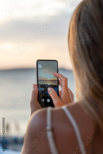 Mujer de espalda fotografiando el atardecer