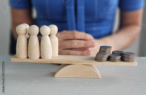 Balancing wooden figures and coins illustrates economic disparity in a contemporary financial