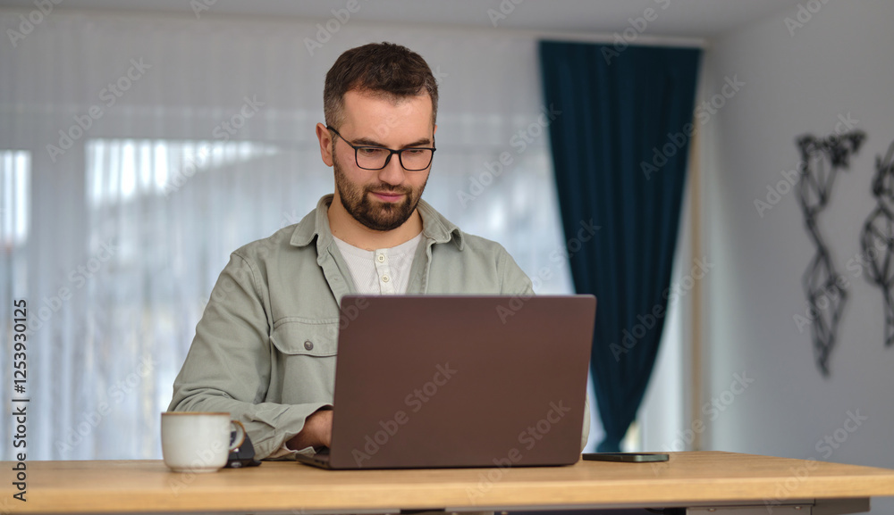 A young man using a laptop while working at home. A young man using a laptop while working at home.