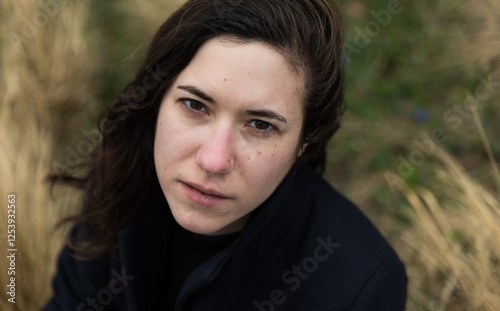 Emotive headshot of a dark haired 27 yo white woman with a nature background, Brussels, Belgium