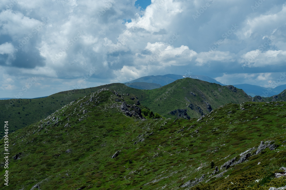 A vibrant green mountainous landscape, captured during spring, with dramatic clouds under a clear blue sky. Ideal for nature, landscape, and environmental photography themes - Bulgaria, Europe A vibrant green mountainous landscape, captured during spring, with dramatic clouds under a clear blue sky. Ideal for nature, landscape, and environmental photography themes - Bulgaria, Europe