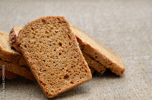 Whole grain rye bread slices on rustic linen cloth photo