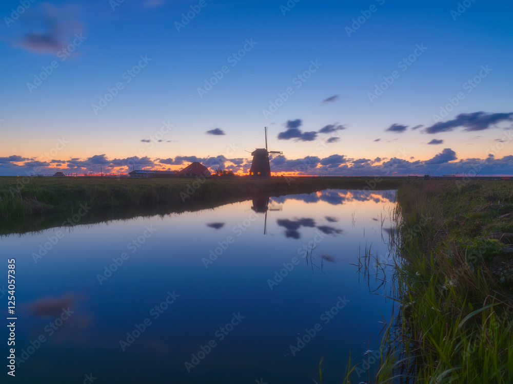 Windmill in the Netherlands. Historical buildings in the Netherlands. Reflections on the surface of water. Image for postcards, background, design. Landscape during sunset. Windmill in the Netherlands. Historical buildings in the Netherlands. Reflections on the surface of water. Image for postcards, background, design. Landscape during sunset.