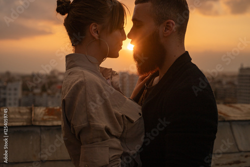 A couple shares an intimate moment on a rooftop during a vibrant sunset, expressing romance and connection.
