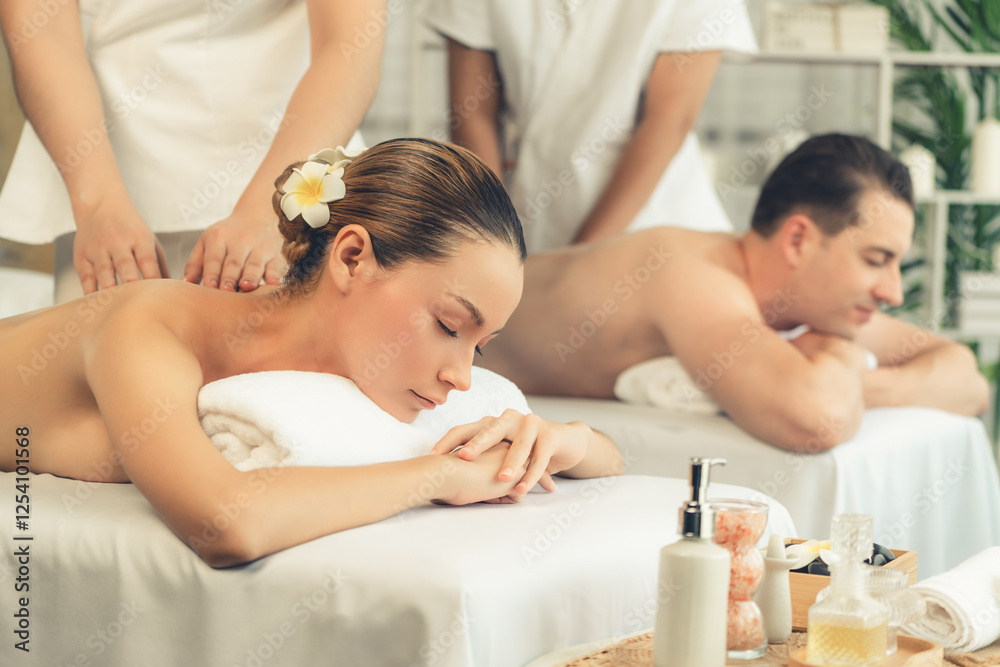 Caucasian couple customer enjoying relaxing anti-stress spa massage and pampering with beauty skin recreation leisure in day light ambient salon spa at luxury resort or hotel. Quiescent Caucasian couple customer enjoying relaxing anti-stress spa massage and pampering with beauty skin recreation leisure in day light ambient salon spa at luxury resort or hotel. Quiescent
