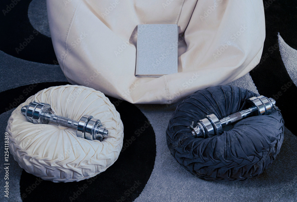 Dumbbells and book resting on cozy cushions ready for home workout