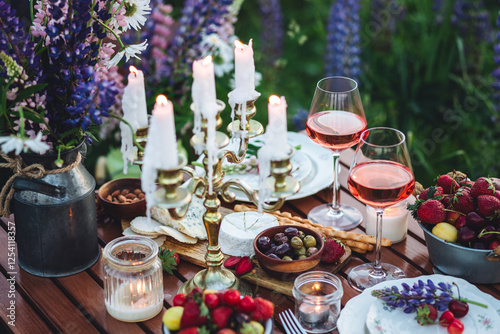 Perfect surprise date for loving couple, private wedding, romantic marriage proposal. Summer, sunset, golden hour. Appetisers. Beautiful elegant outdoor arrangement in meadow with purple blue lupins photo