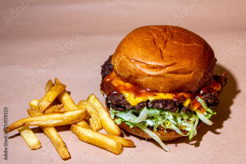 A delicious burger with a golden crust, with juicy meat, salad, a slice of melted cheese and ketchup, with golden fries on the side