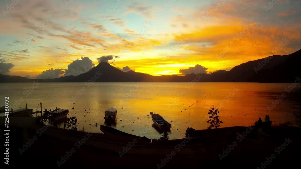 Timelapse Panoramic view of Lake Atitlan in Guatemala in the evening with rich flowers of sunset and some boats in the foreground. Timelapse Panoramic view of Lake Atitlan in Guatemala in the evening with rich flowers of sunset and some boats in the foreground.
