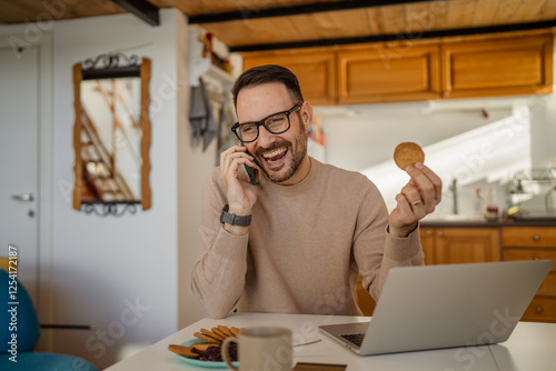 Adult caucasian man eat breakfast talk on mobile phone work from home photo