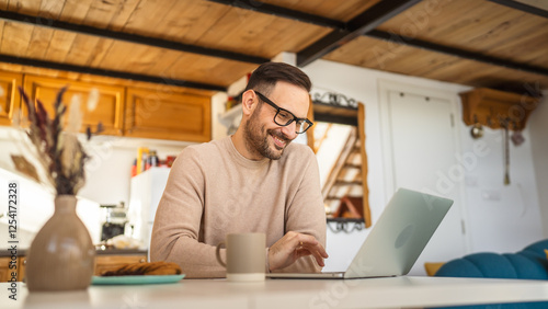 Adult man hold coffee work from home on laptop with cookies on table photo