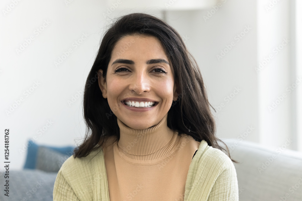 Head shot profile picture of beautiful Brazilian woman revealing white teeth while smiling at camera sit on cozy sofa at home, having natural beauty and positive, joyful expression. Homeowner portrait Head shot profile picture of beautiful Brazilian woman revealing white teeth while smiling at camera sit on cozy sofa at home, having natural beauty and positive, joyful expression. Homeowner portrait