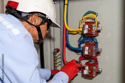 Latin electrical engineer performs maintenance on an industrial circuit