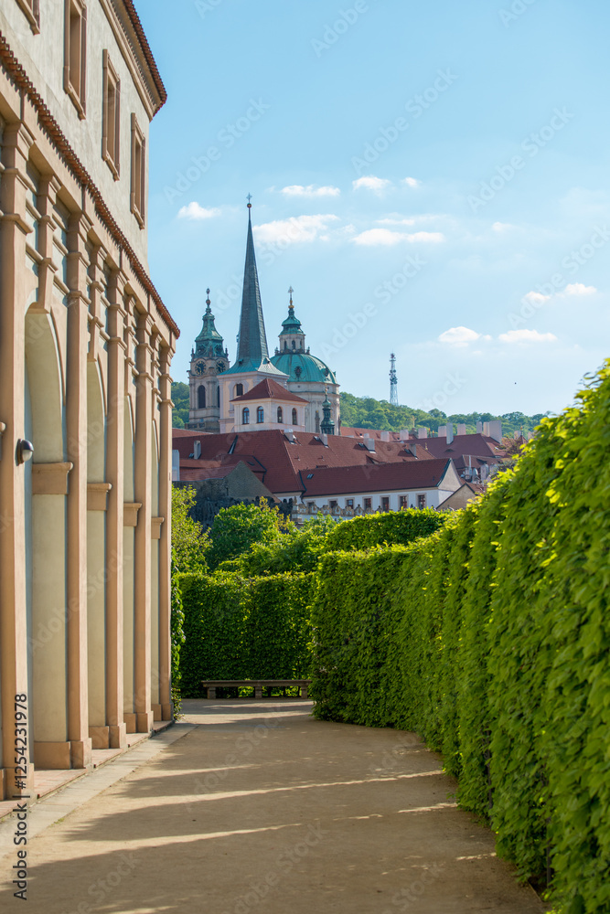 Obraz premium Beautiful garden path with historical buildings in Prag under clear blue sky