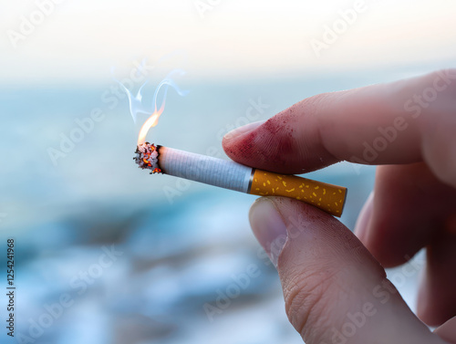 Quitting smoking according to the concept of drug addiction treatment. close up of nicotine stained fingers holding lit cigarette by sea
