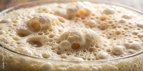 A close-up of a bubbly sourdough bread dough starter with frothy foam and yeast cells, showcasing its fermentation process