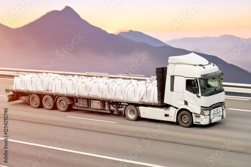 Open-Flatbed Truck Transporting Fertilizer in Bulk Big Bags Sacks Across Mountainous Terrain photo