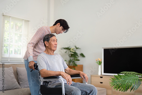 Son guiding elderly father in wheelchair while sitting in living room at home. photo