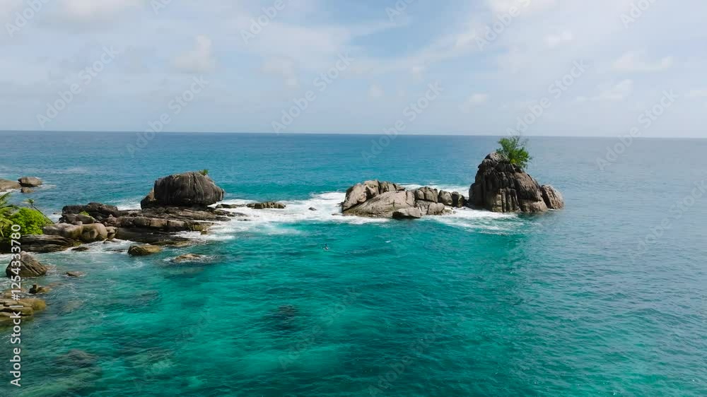 Rock formations surrounded by clear turquoise water with gentle waves on a sunny day. Seychelles, Mahe. Rock formations surrounded by clear turquoise water with gentle waves on a sunny day. Seychelles, Mahe.