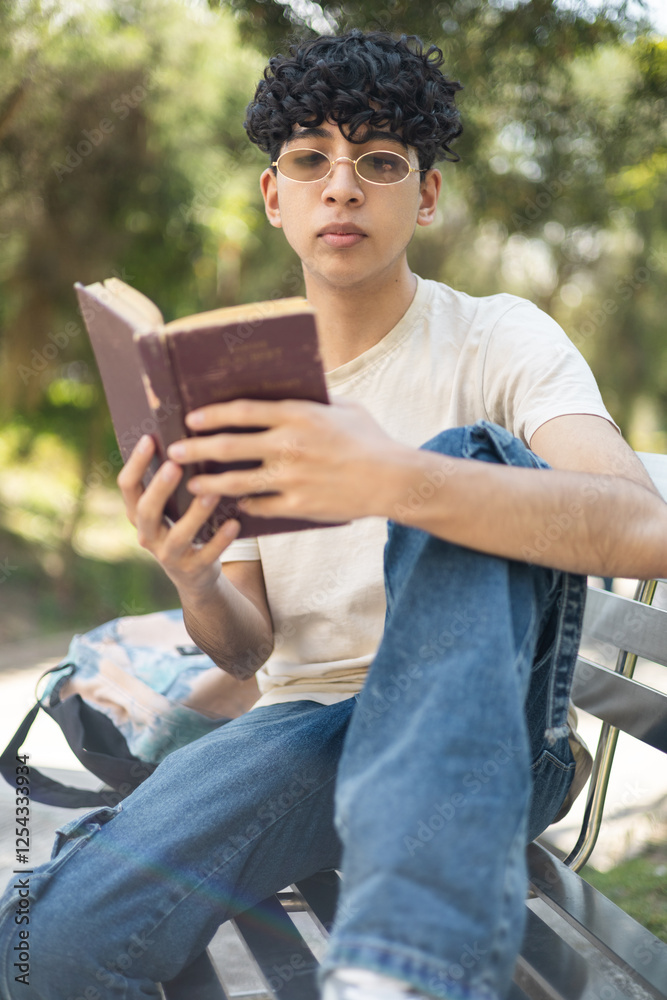 Fototapeta premium Enjoying a peaceful moment in the park, reading a book under the sun, perfect for themes like relaxation, outdoor activities, and leisure time.