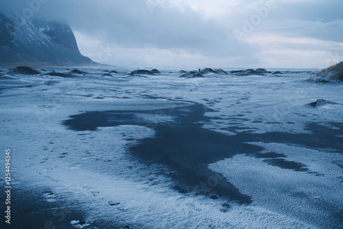 Canvas Print A frozen Icelandic landscape with a dark icy lake contrasting against the surrounding snow-covered terrain