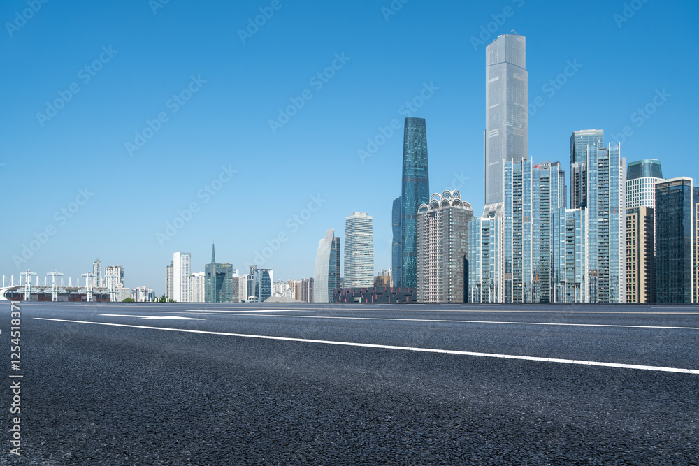 Modern Urban Skyline with Clear Blue Sky and Empty Road Modern Urban Skyline with Clear Blue Sky and Empty Road