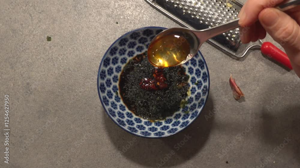 A cook mixes a dipping sauce with soy, garlic, ginger, fish sauce, and chili. A cook mixes a dipping sauce with soy, garlic, ginger, fish sauce, and chili.