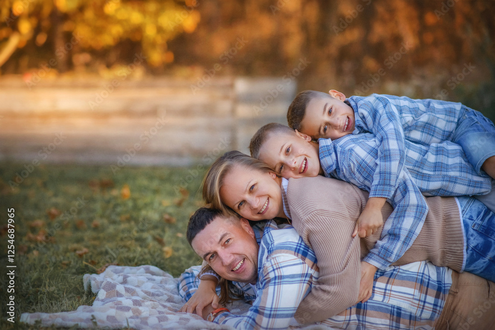 A large family is relaxing in the village. A family on a picnic. Mom and Dad are lying on the grass, and the sons are lying on top of each other. The family is in a good mood, smiling! A large family is relaxing in the village. A family on a picnic. Mom and Dad are lying on the grass, and the sons are lying on top of each other. The family is in a good mood, smiling!