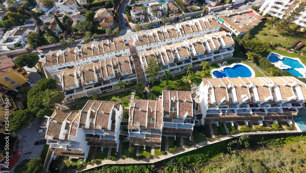 Fototapeta premium Aerial drone photo of the beautiful town of Sitio de Calahonda in Malaga Spain showing a bird's eye view of residential and holiday homes with swimming pools from above on a sunny day