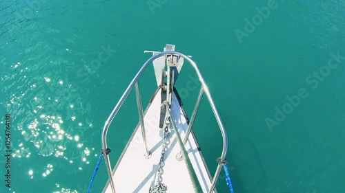 Sailboat bow gliding smoothly lake turquoise water sparkling sunlight