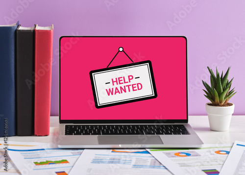 Laptop showing help wanted sign on pink screen with documents on desk