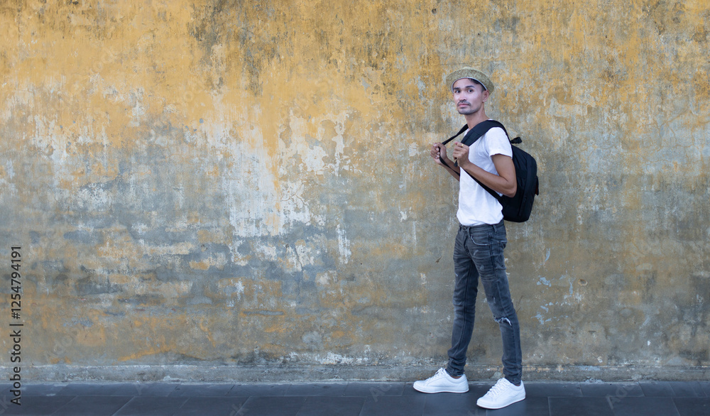 traveler man walking and looking at camera with mustard yellow wall background at Merchant heritage House ,Back door in Hoi an at Vietnam traveler man walking and looking at camera with mustard yellow wall background at Merchant heritage House ,Back door in Hoi an at Vietnam
